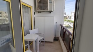 A balcony with a table and chairs, an air conditioning unit, and a view of buildings. - Rocha's Corner (Portimão)