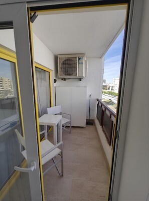 A balcony with a table and chairs, an air conditioning unit, and a view of buildings. - Rocha's Corner (Portimão)