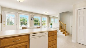 A kitchen with a dishwasher, wooden cabinets, and a window overlooking a garden.