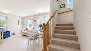 A spacious living room with a staircase, a dining area, and a view of the outdoors.