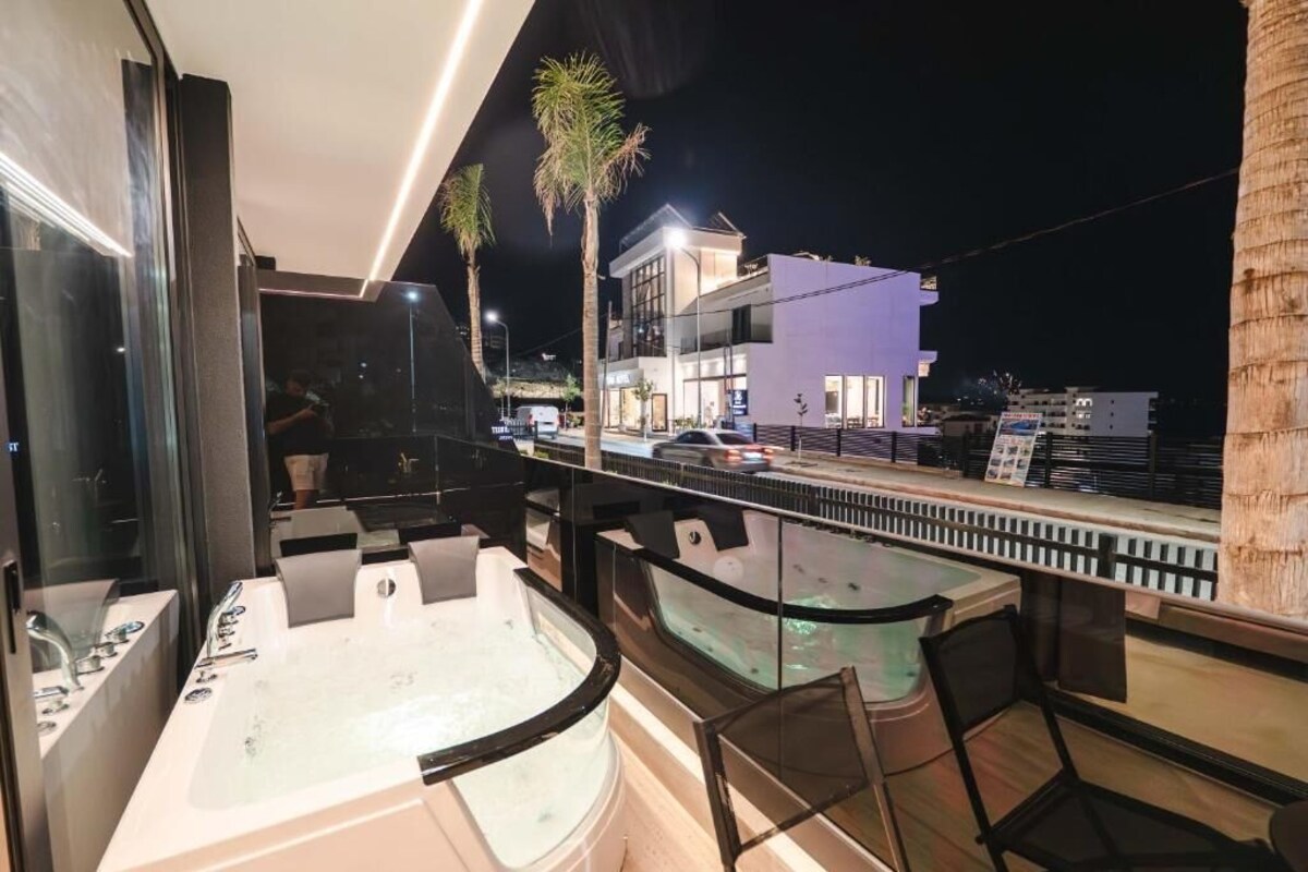 A rooftop bar with a jacuzzi, outdoor seating, and a view of a cityscape at night.