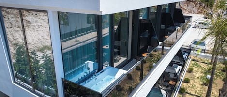 Un edificio moderno con amplios ventanales, piscina en la azotea y zona de estar al aire libre.