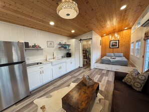 A modern kitchen with white cabinets, a stainless steel refrigerator, and a wooden ceiling. - Liberty-Cabin-2 @ Eagle Hollow (goreville)