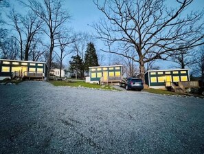 A gravel driveway leading to a row of two-story buildings with a car parked in front. - Justice-Cabin-3 @ Eagle Hollow (goreville)