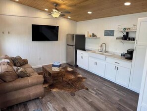 A modern kitchen with white cabinets, a black refrigerator, and a wooden ceiling. - Justice-Cabin-3 @ Eagle Hollow (goreville)