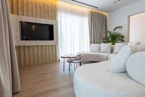 A modern living room with a flat-screen TV mounted on a wall, a sofa, a small coffee table, and a potted plant.