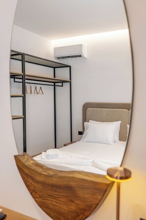 Un dormitorio con literas, una mesita de noche, una lámpara y un equipo de aire acondicionado.