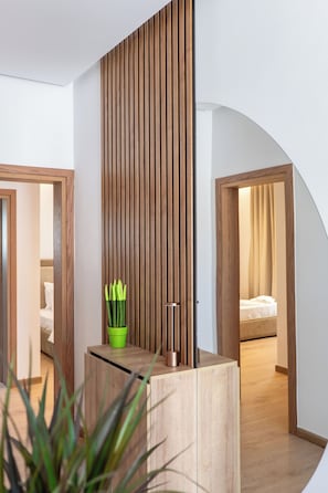 A modern hotel room with a wooden partition, a green plant, and a bed with a beige curtain.