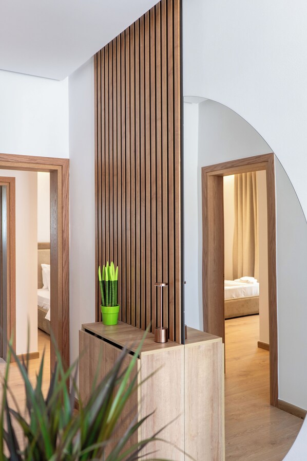 A modern hotel room with a wooden partition, a green plant, and a bed with a beige curtain.