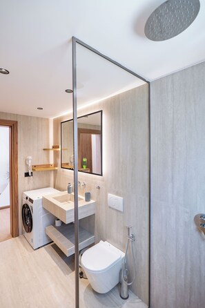 Un baño moderno con lavadora integrada, inodoro y ducha.