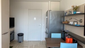 Eine kleine Küche mit Kühlschrank, Herd und Mülleimer.