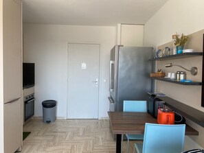 A compact kitchen with a refrigerator, stove, and trash bin. - Cannes Marina Studio with Harbor View, Pool (Mandelieu-la-Napoule)