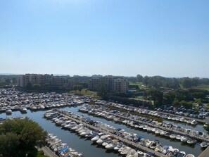 A marina with numerous boats docked, surrounded by residential buildings and greenery. - Cannes Marina Studio with Harbor View, Pool (Mandelieu-la-Napoule)