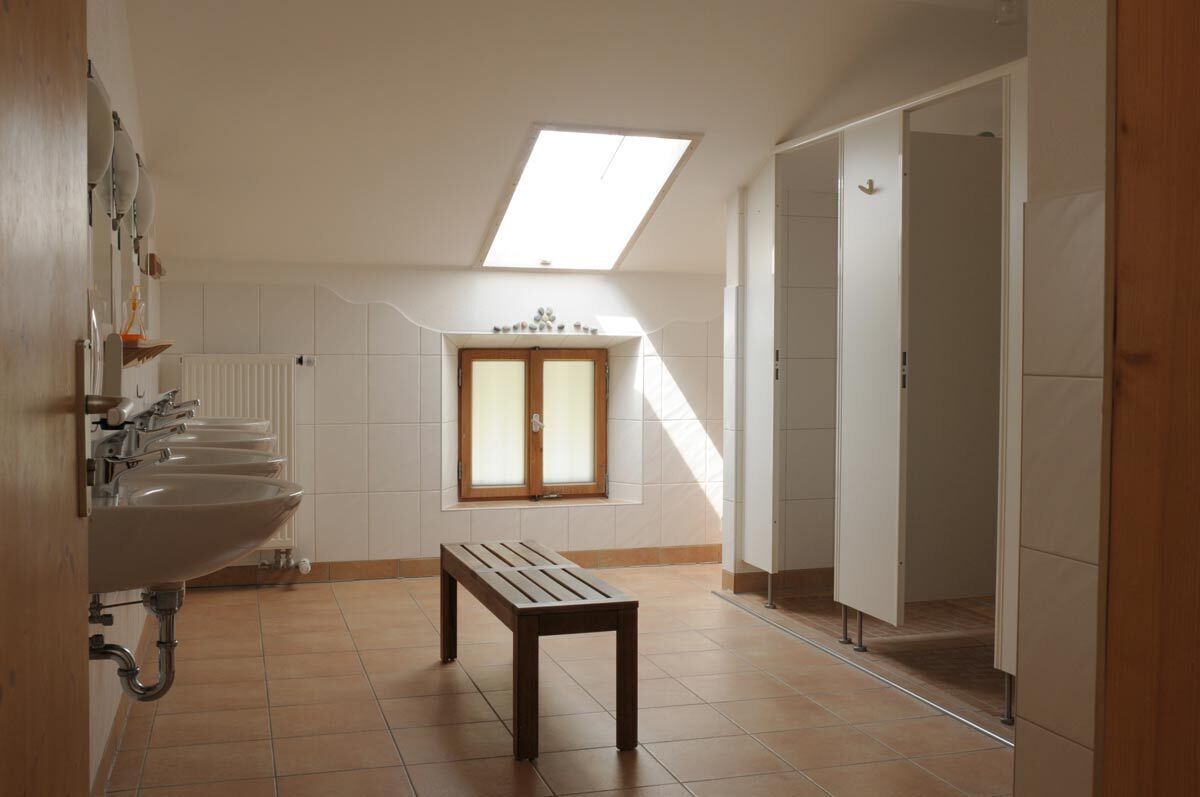 Ein Badezimmer mit Oberlicht, einer Sitzbank und mehreren Waschbecken.