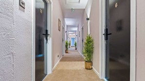 Ein Hotelgang mit Teppichböden, Zimmertüren auf beiden Seiten und Topfpflanzen.