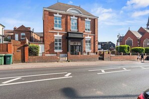 A two-story brick building with a black storefront and a gated entrance. - Stylish Double Bed Studio + Parking | Coventry CV2 (Coventry)