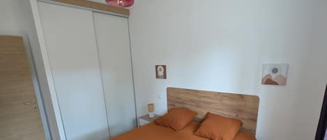 A bedroom with a bed, a wardrobe, a nightstand, and a red hanging lamp.