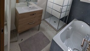 Un baño con ducha de vidrio, un lavabo blanco con espejo y una bañera.