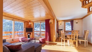 L’intérieur d’un chalet en bois, avec un canapé, une table à manger, des chaises et un téléviseur.