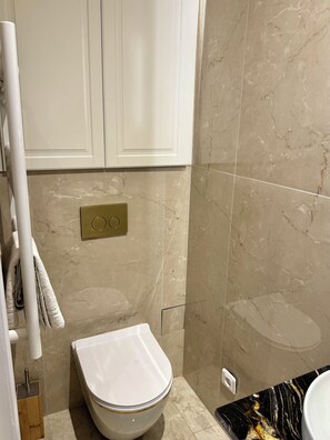 Een badkamer met toilet, handdoekhouder en een marmeren muur.