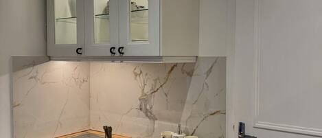 A compact kitchen with a built-in dishwasher, a wooden countertop, and a white door.