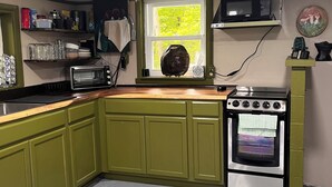 Une cuisine avec des meubles de couleur verte, un four à micro-ondes, un grille-pain et une cuisinière.