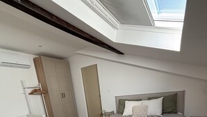 Ein Schlafzimmer mit Oberlicht, Bett, Kleiderschrank und Nachttisch.