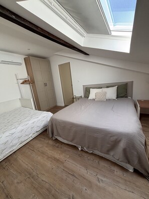 Een slaapkamer met dakraam, een bed, een kledingkast en een nachtkastje.