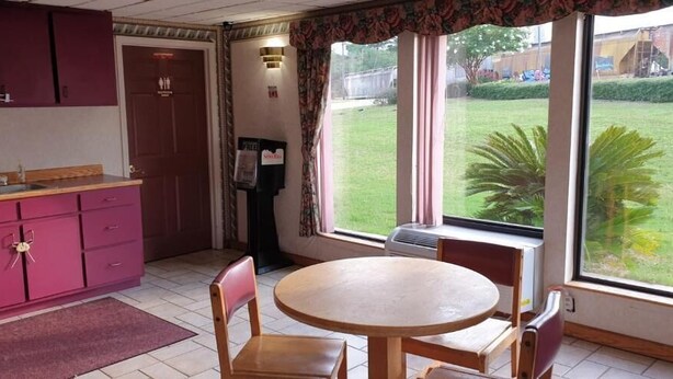 A kitchen with a dining table and chairs, a window with a view of a grassy area, and a door with a sign.