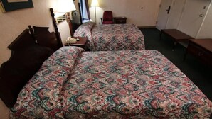 A hotel room with two beds, a desk, a chair, and a wardrobe.