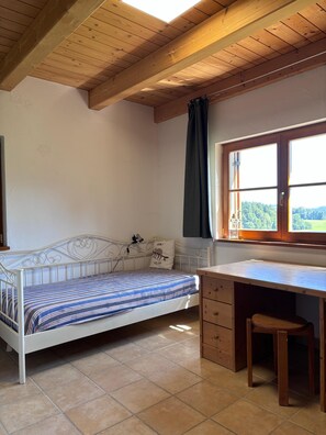 Un dormitorio con cama, escritorio y ventana.