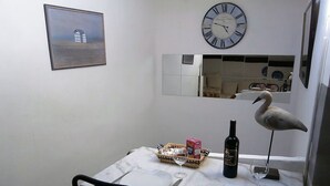 A dining area with a table set for two, a clock on the wall, and a bird sculpture. - Spacious loft apartment in charming Saint-Chinian (saint-Chinian)