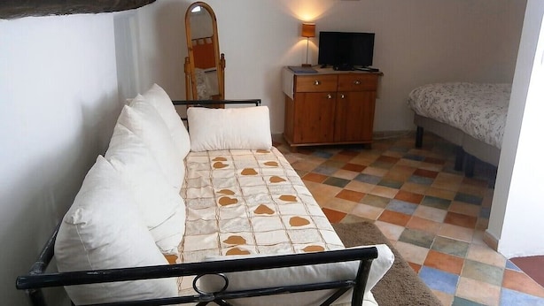 A small, cozy room with a sofa, a wooden cabinet, and a bed. - Spacious loft apartment in charming Saint-Chinian (saint-Chinian)
