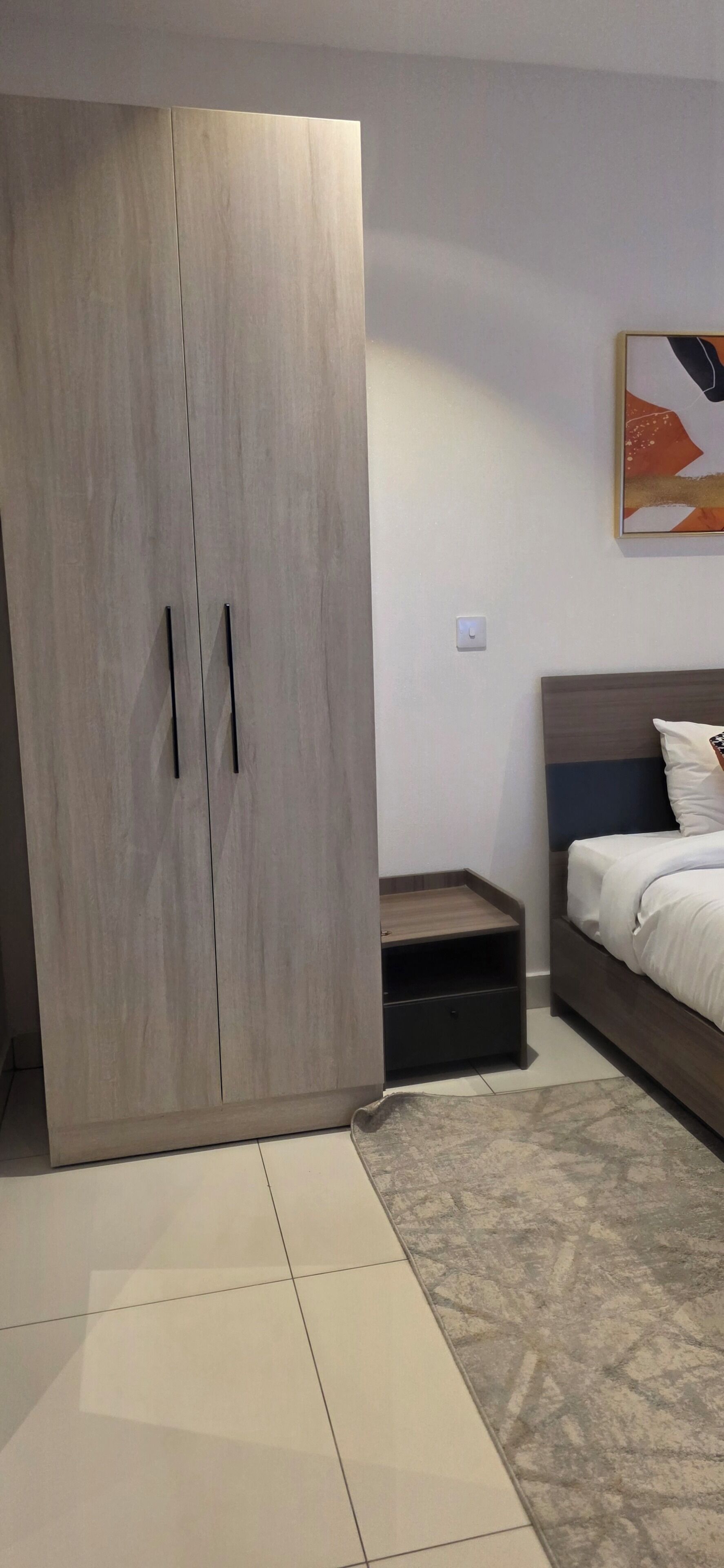 Ein Schlafzimmer mit Bett, Kleiderschrank, Nachttisch und einem Wandbild.