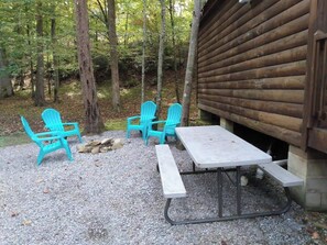 A rustic wooden cabin with a gravel patio, two turquoise Adirondack chairs, and a picnic table. - Pet Friendly Cabin in Gatlinburg (Gatlinburg)