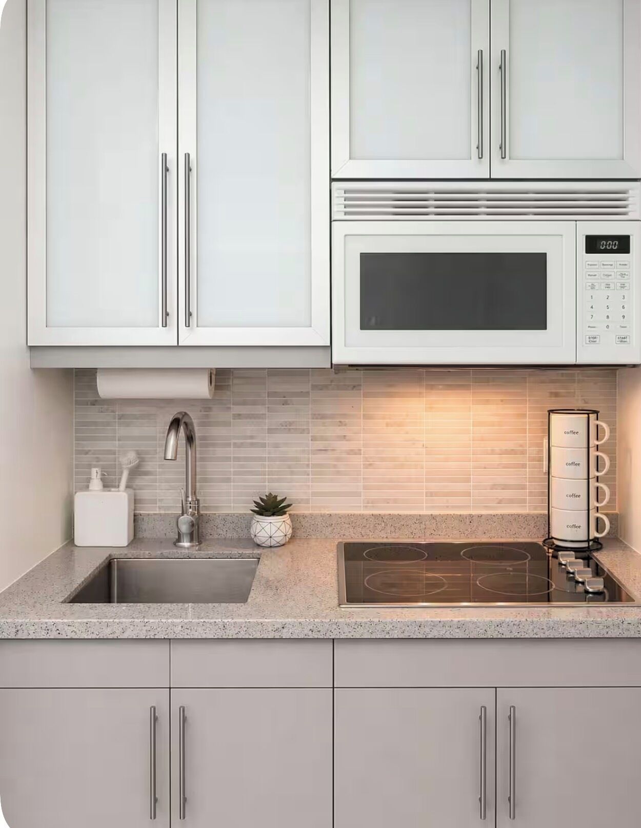 Una cocina con un lavaplatos de acero inoxidable, un microondas y una estufa empotrada.