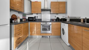 Eine moderne Küche mit Holzschränken, Edelstahlgeräten und einem eingebauten Backofen.