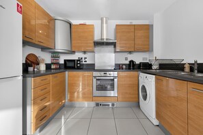 Eine moderne Küche mit Holzschränken, Edelstahlgeräten und einem eingebauten Backofen.