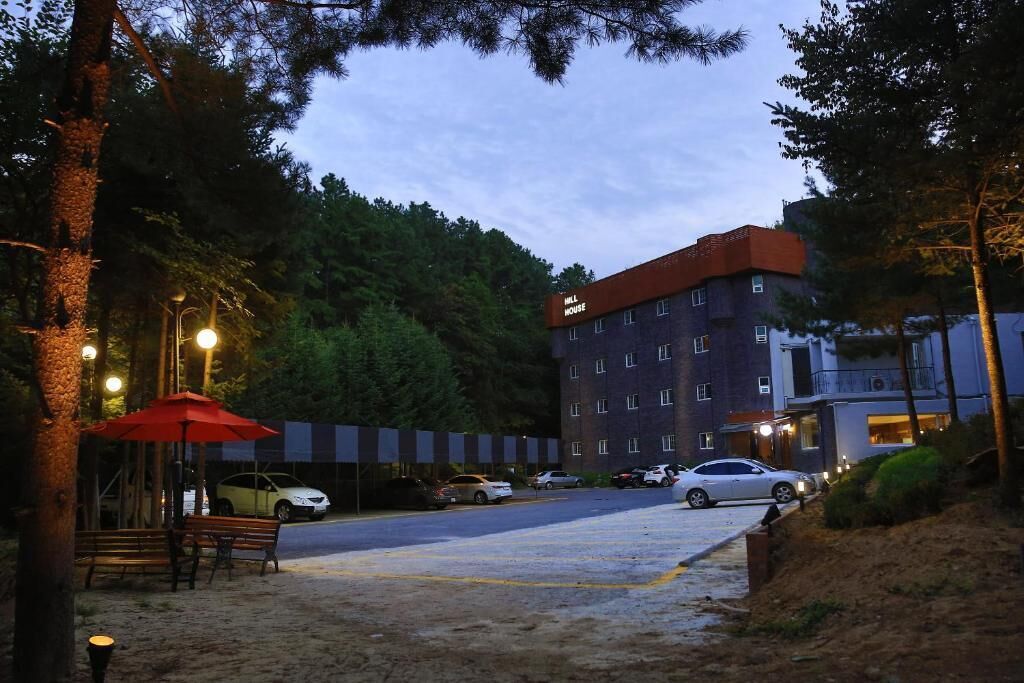 A hotel with a parking lot, a red umbrella, and a building with multiple windows.