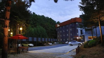 A hotel with a parking lot, a red umbrella, and a building with multiple windows.