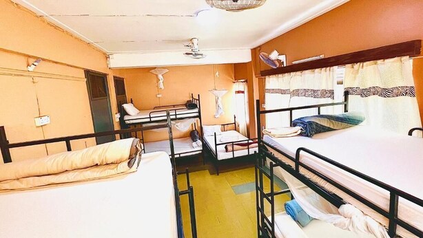 Una camera in stile dormitorio con letti a castello, un tavolino e una ventola a soffitto.
