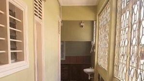 Un corridoio con tappeto rosso, una porta con finestra e una parete decorativa sulla destra.