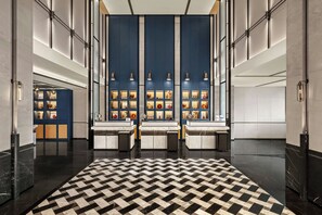 A lobby with a checkered floor, a reception desk, and a wall with shelves displaying various items. - Four Points by Sheraton Guilin Central (Guilin)