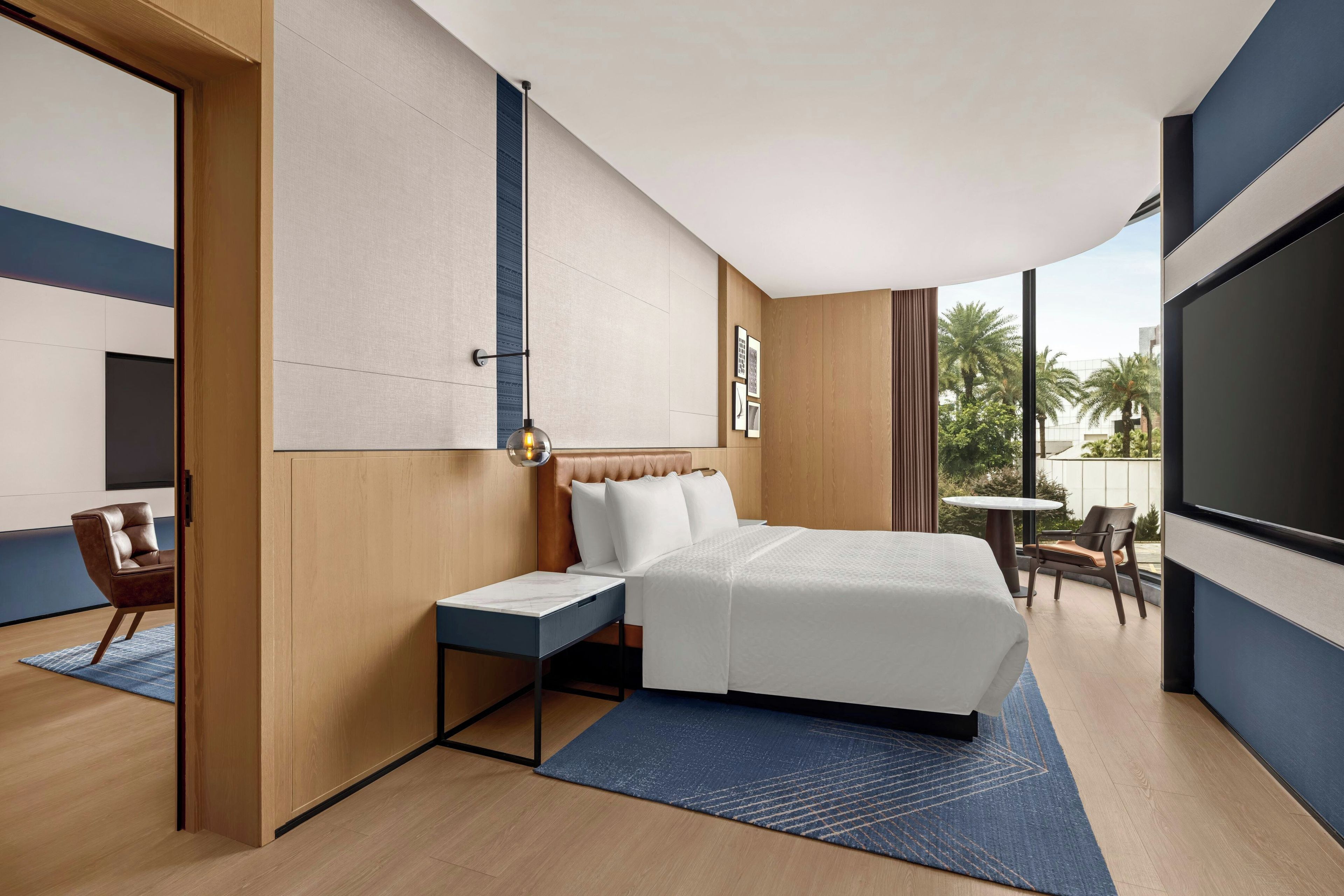 A modern hotel room with a bed, bedside table, and a TV.