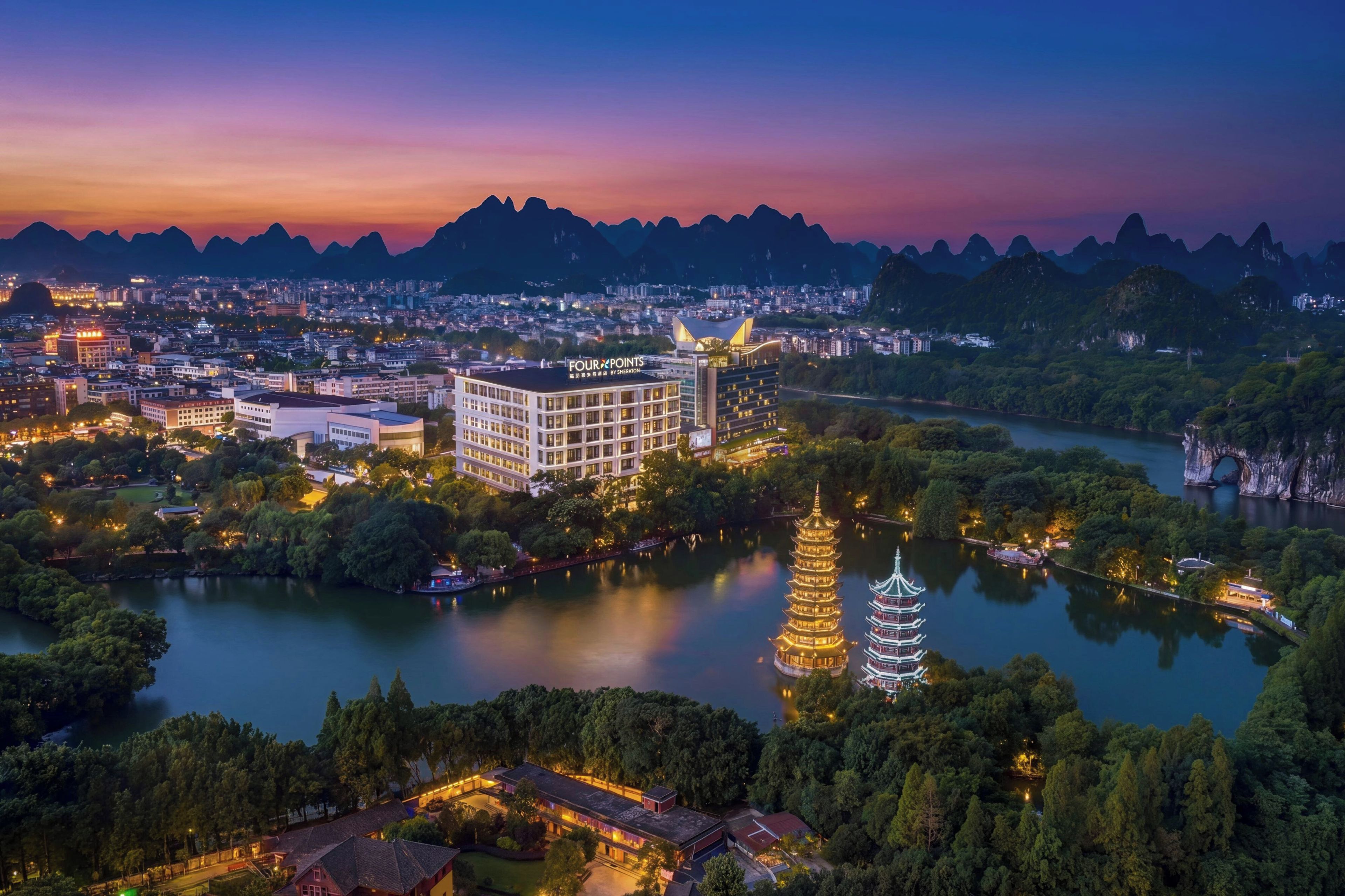 Un paisaje urbano con un hotel destacado, un río y una pagoda.