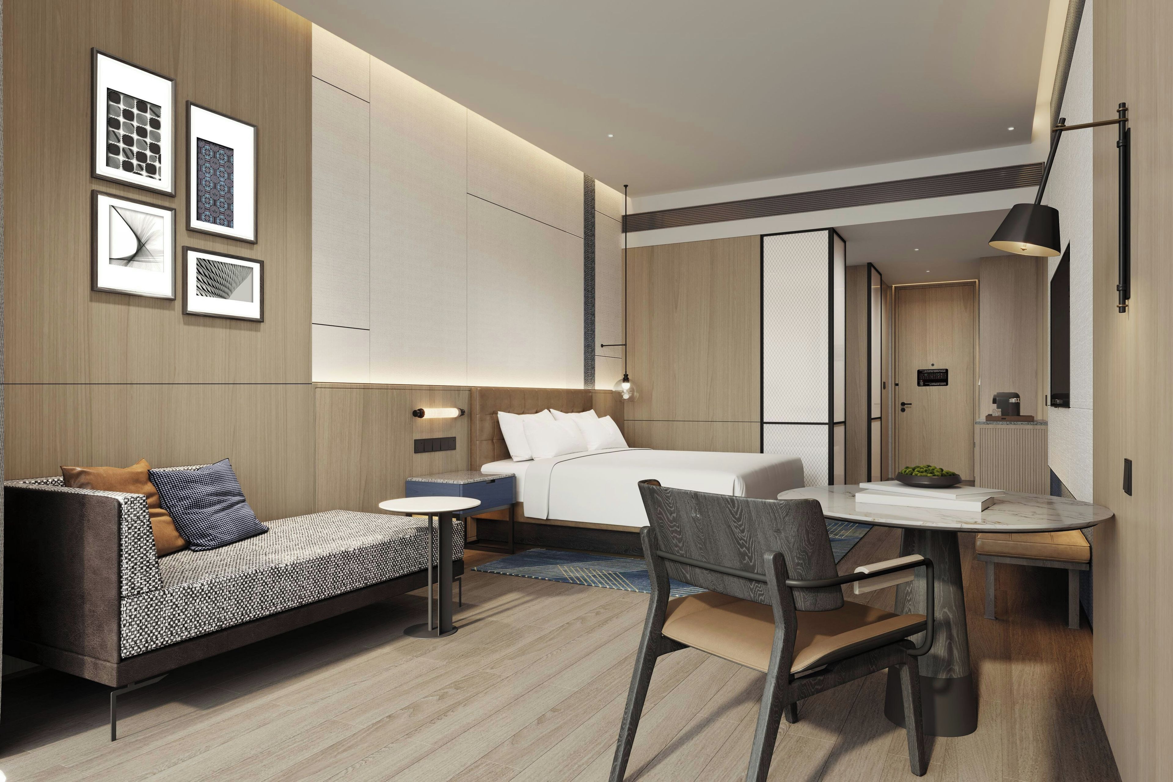 A modern hotel room with a bed, a sofa, a dining table, and a chair.