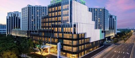 A modern hotel building with a glass facade, multiple floors, and a prominent entrance.