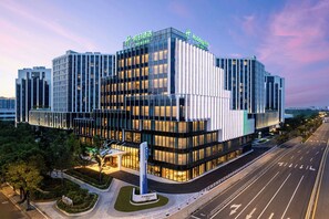 Un moderno edificio de hotel con fachada de vidrio, varios pisos y una entrada destacada.