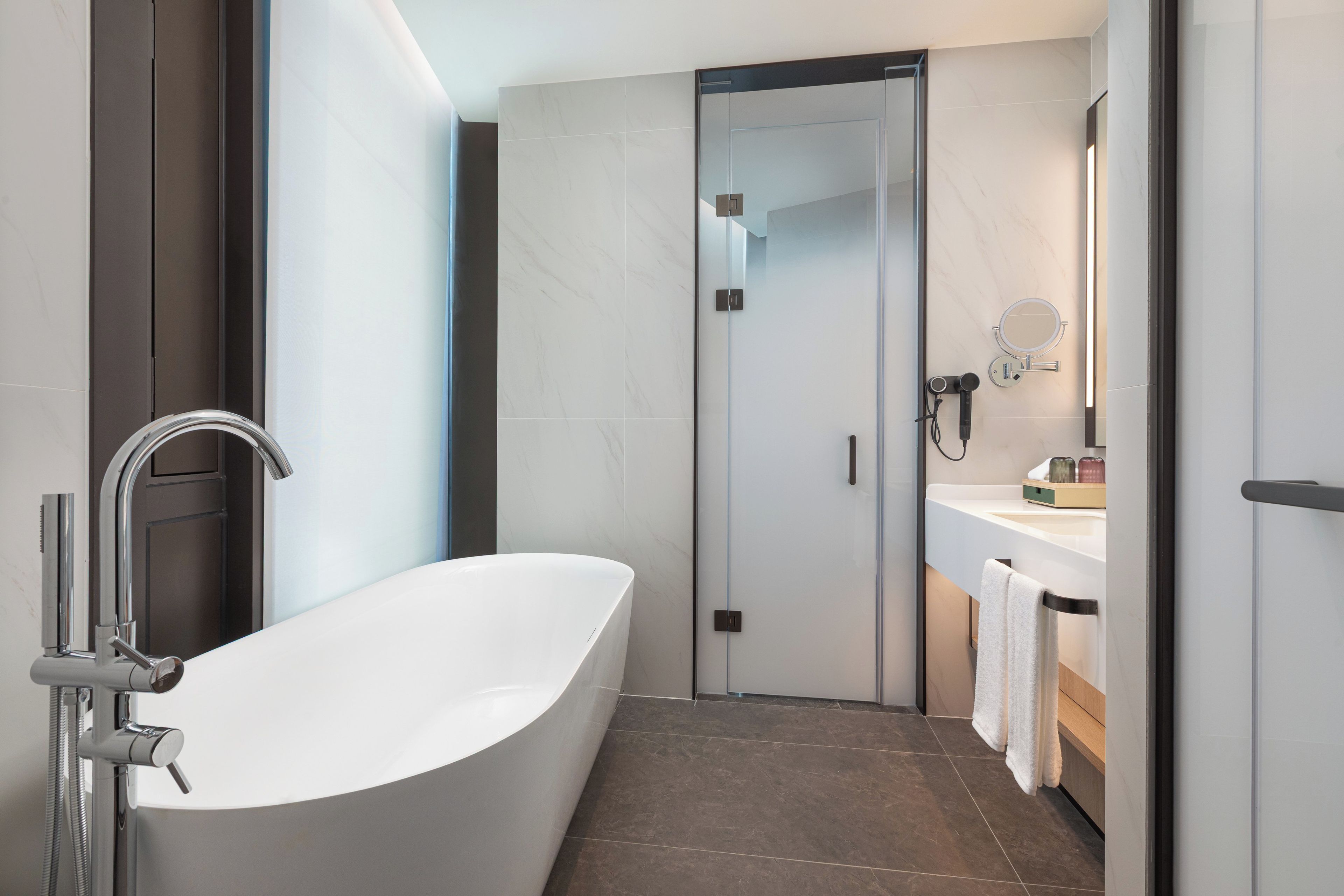 Un baño moderno con una bañera independiente, una ducha con mampara de vidrio y un tocador con espejo.
