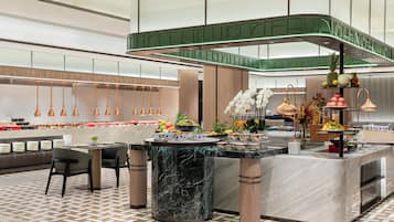 Un hall d’hôtel moderne avec un comptoir d’accueil en marbre, un espace salon et un présentoir de fruits.